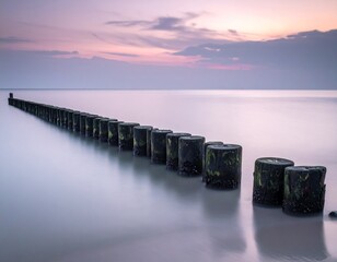 A wooden breakwater at grey misty dawn in a still sea, long exposure 