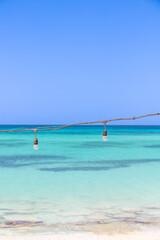 VIew of the amazing beach of Playa de la Cueva, Cabo Rojo, Dominican Republic, near the border with Haiti. Tranquil, crystal clear, turquoise Caribbean sea. A string of lights in the frame. Peaceful