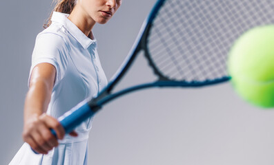 Young Female Tennis Player Hitting Ball on Neutral Background