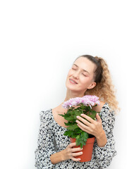 Blonde woman with curly hair holding and hugging a chrysanthemum plant, symbol of love for flowers and home comfort