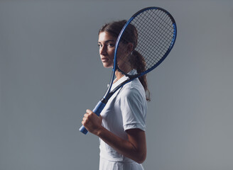 Beautiful Young Brunette Tennis Player Posing with Racquet on Gray Background