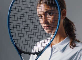 Close-Up Portrait of Beautiful Brunette Tennis Player with Racquet on Gray Background