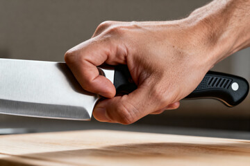 Close up of Chef hand holding professional kitchen knife ready to chop ingredients on cutting board