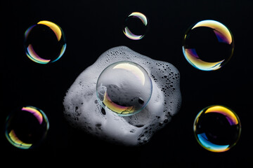 Iridescent soap bubbles cluster on a black background with glittering hues.