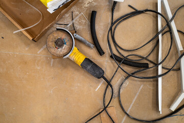 Overhead shot of a chaotic workbench with a grinder, various cables, and scraps.