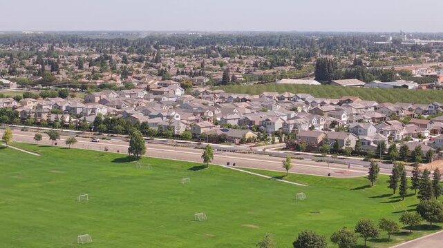 Drone moving forward over soccer ground toward houses and road.