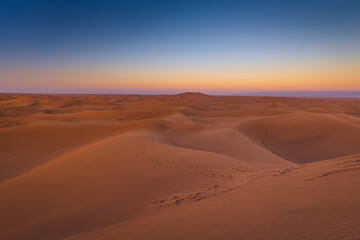 Golden dunes of the Sahara Desert in Morocco at sunset – scenic sand landscape with waves of dunes and dramatic light in North Africa