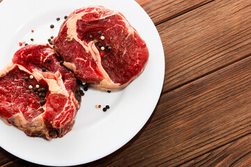 Freshly cut ribeye steaks ready for cooking on a plate