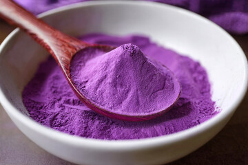 Close-up of purple sweet potato powder, also known as ube powder,  on a brown wooden spoon in white Japanese-style bowl. Bright and soft natural lighting.  Generated image