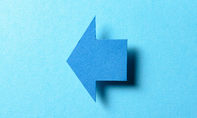 Blank paper cardboard arrow direction sign with shadow and copy space for text on blue background, flat lay top view pointing symbol conceptual message backdrop