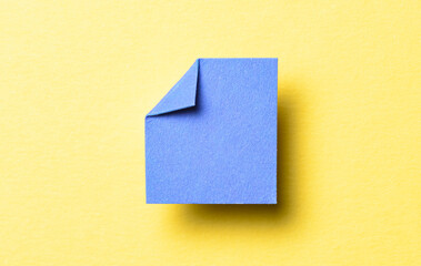 Blue blank paper note cardboard with folded corner dog-ear earmark, shadow and copy space for text on yellow background