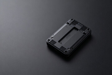 Black plastic electronic component with rectangular cutout and mounting slots on a dark surface