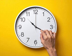 Hand adjusting the time on a white clock with a yellow background.