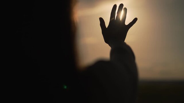 Silhouette of hand reaching for sun. Hand extended towards sun in nature. Concept of hope and aspiration. Silhouette against sun in natural setting. Inspirational moment of hand and sun in nature.