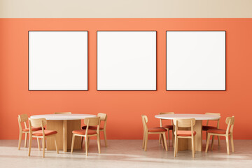 Modern interior with round tables and blank square posters on orange wall in minimalist dining or cafe setting. 3D Rendering