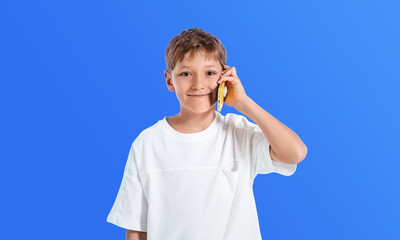 Smiling boy holding banana like a phone, wearing white shirt, st