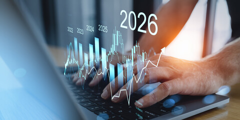 Hands typing on laptop with futuristic financial chart projections showing data trends from 2022 to 2026 on transparent interface concept.