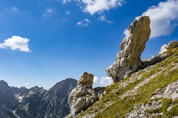 Dramatic view of Babe rock formation near Kamniško sedlo, Slovenia, with rugged alpine terrain, clear skies, and a scenic mountain hiking trail.