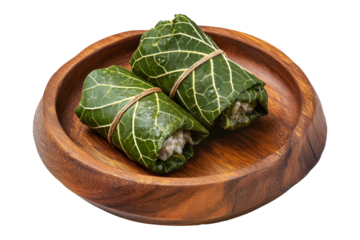 Mini Lu Pulu beef wraps filled with coconut cream in taro leaves on wooden plate, isolated on white transparent background. Concept of healthy vegetarian appetizer