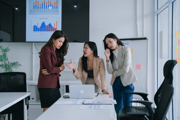 Three businesswomen engaged in a heated argument during an office meeting. With one woman gesturing...
