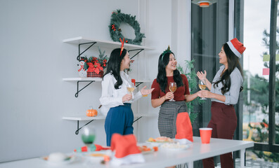 Group of diverse women friends enjoying a festive Christmas office party, laughing, talking, and drinking wine, creating a joyful and relaxing atmosphere during the holiday season
