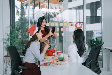 Colleagues wearing festive headwear and Santa hats celebrate the Christmas holiday office party,...