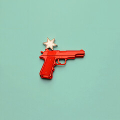 Red toy gun with a white star resting on top against a light blue background in a studio shot