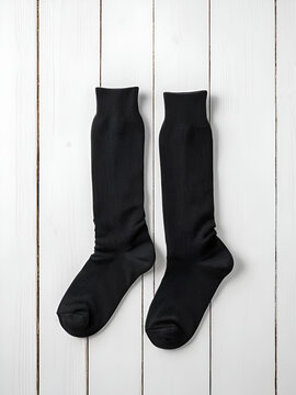 Pair blank black tall socks side view flat lay on white wood board as mock up for design, print, presentation, advertising, top view, copy space.