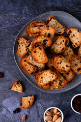 Rusks with dried cranberries and pistachios on ceramic plate on grey table