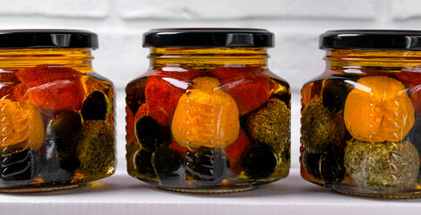 Labneh yogurt cheese balls in spices in glass jars with olives on white background. Middle Eastern cuisine dish