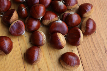 Many ripe chestnuts  on wooden background on selective focus. Castanea sativa seeds