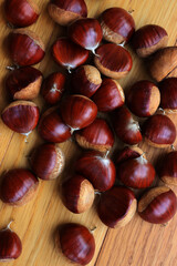 Many ripe chestnuts  on wooden background on selective focus. Castanea sativa seeds