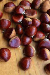 Many ripe chestnuts  on wooden background on selective focus. Castanea sativa seeds