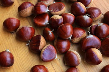 Many ripe chestnuts  on wooden background on selective focus. Castanea sativa seeds