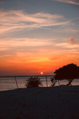 Floating in the waves at sunset, sun just above horizon, going down, orange sky, tranquil sea. Peaceful moment, vacations, summer mood. Dominican Republic. Horizontal video.