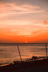 Floating in the waves at sunset, sun just above horizon, going down, orange sky, tranquil sea. Peaceful moment, vacations, summer mood. Dominican Republic. Horizontal video.