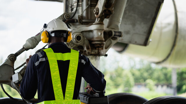 Aircraft maintenance engineer inspecting airplane engine with safety equipment and tools, aviation mechanic ensuring aircraft repair, safety check, and technical engineering service.