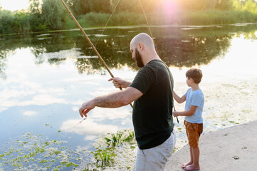 Father and son fishing together at river during sunset