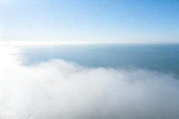 Obraz premium Aerial view of clouds above a calm ocean under clear blue sky