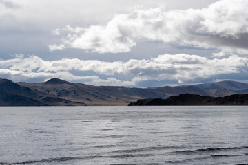 A landscape with a lake against the backdrop of steppe and mountains on an autumn day in Mongolia.