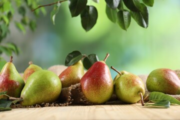 Fresh ripe pears on wooden table and green leaves outdoors, closeup