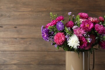 Beautiful flowers in vase against wooden background, closeup. Space for text