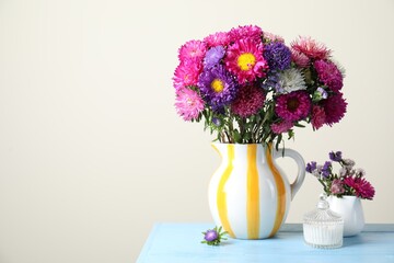 Beautiful flowers in vase on light blue wooden table against grey background. Space for text