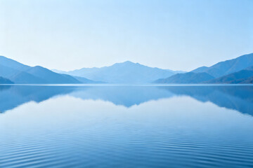 Calm lake reflecting distant mountains under a clear blue sky