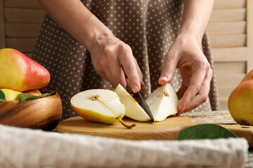 Woman cutting fresh pears at wooden table, closeup