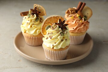 Delicious cupcakes with colorful cream, spices and nuts on grey table, closeup