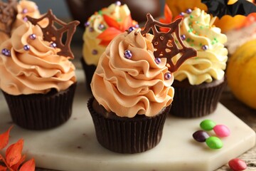 Delicious cupcakes with chocolate web and sprinkles on wooden table, closeup. Halloween celebration