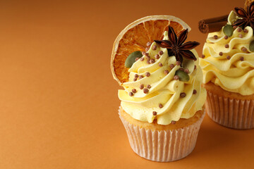 Delicious cupcakes with sprinkles and spices on coral background, closeup with space for text. Autumn atmosphere