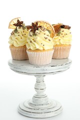 Delicious cupcakes with sprinkles and spices on stand isolated on white. Autumn atmosphere