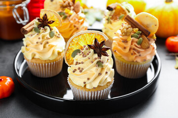 Delicious cupcakes with sprinkles, nuts, cookie and spices on grey table, closeup. Autumn atmosphere